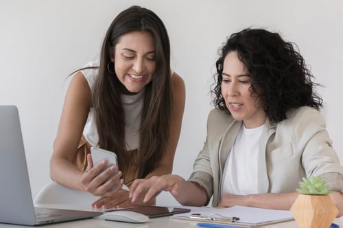 business-woman-showing-her-colleague-something-phone