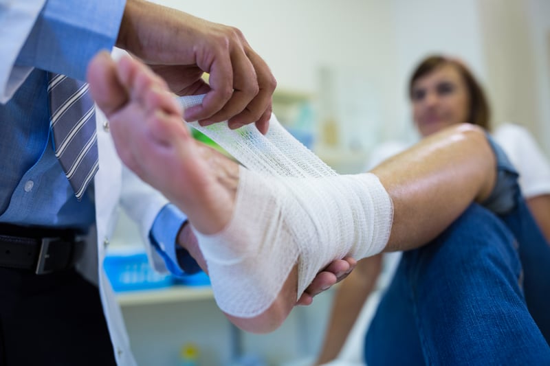 hombres-medico-de-vendaje-del-pie-del-paciente-femenino