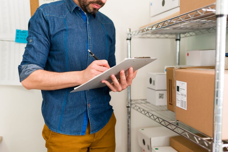joven-latino-y-emprendedor-con-muchos-pedidos-en-su-tienda-online-propietario-de-negocio-escribiendo-la-informacion-de-los-clientes-en-un-portapapeles