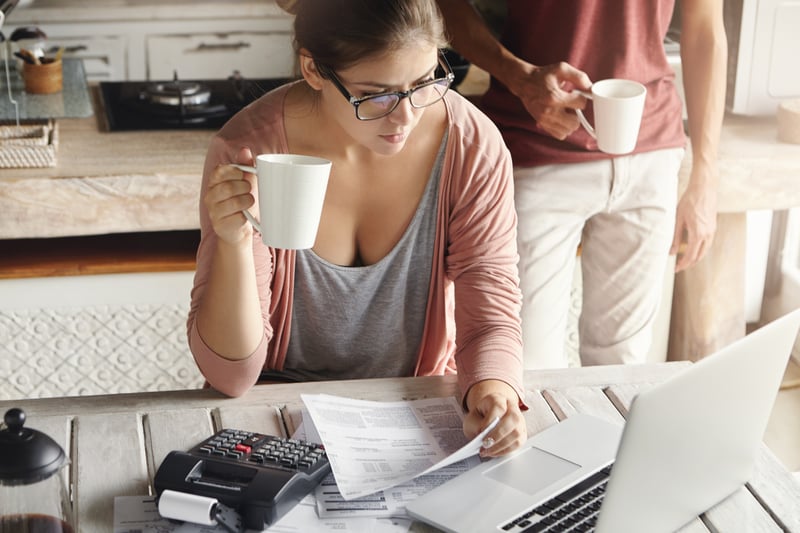 pareja-joven-calculando-los-gastos-familiares-en-casa-mujer-con-gafas-pagando-facturas-de-servicios-publicos-en-linea-tomando-cafe-o-te-sentada-en-la-cocina-con-documentos-y-calculadora-mirando-la-pantalla-del-
