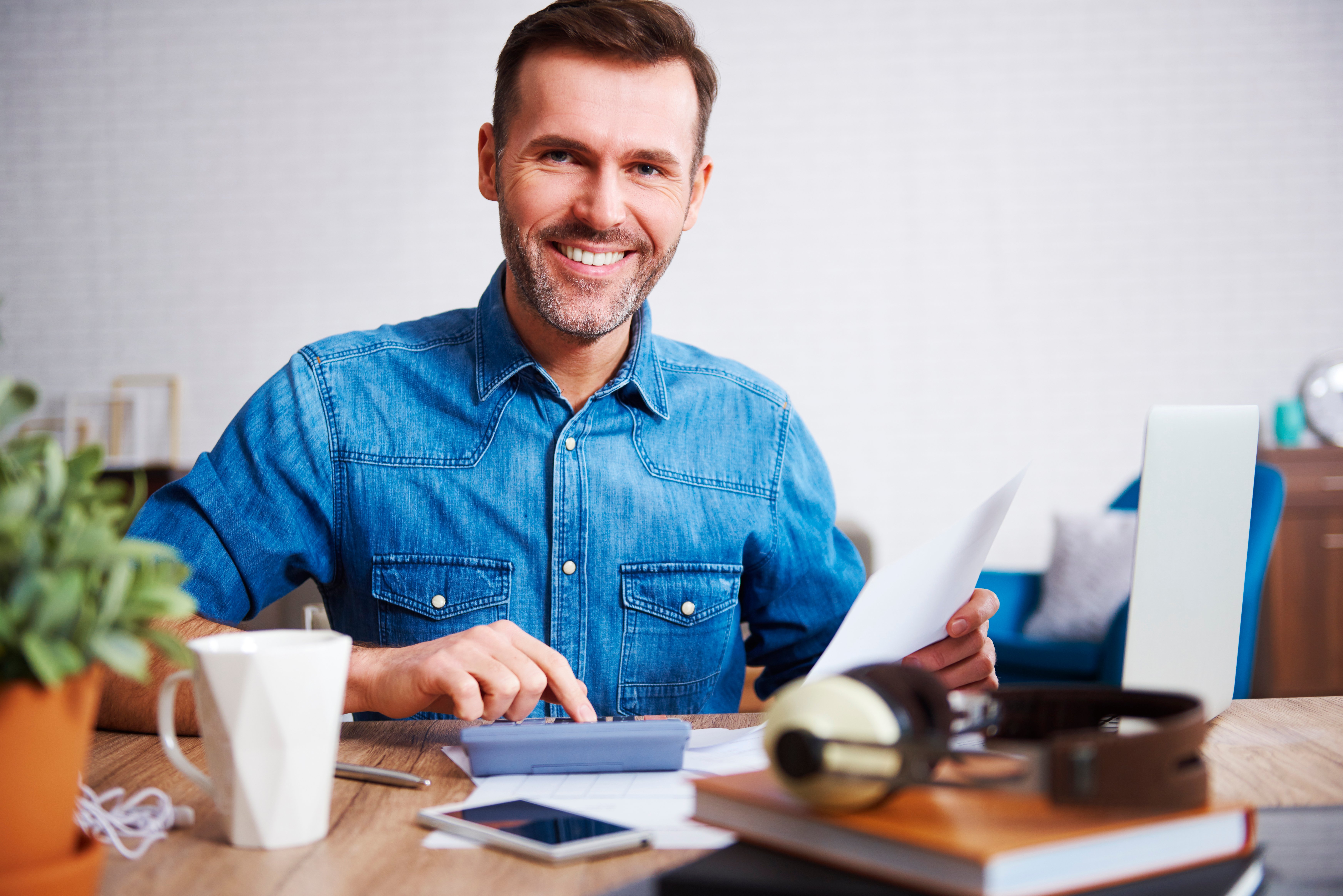 retrato-de-hombre-sonriente-calculando-sus-gastos-mensuales